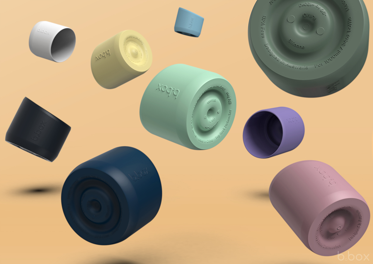 Floating b.box silicone bumper sleeves in assorted colours, shown at different angles on a warm beige background.