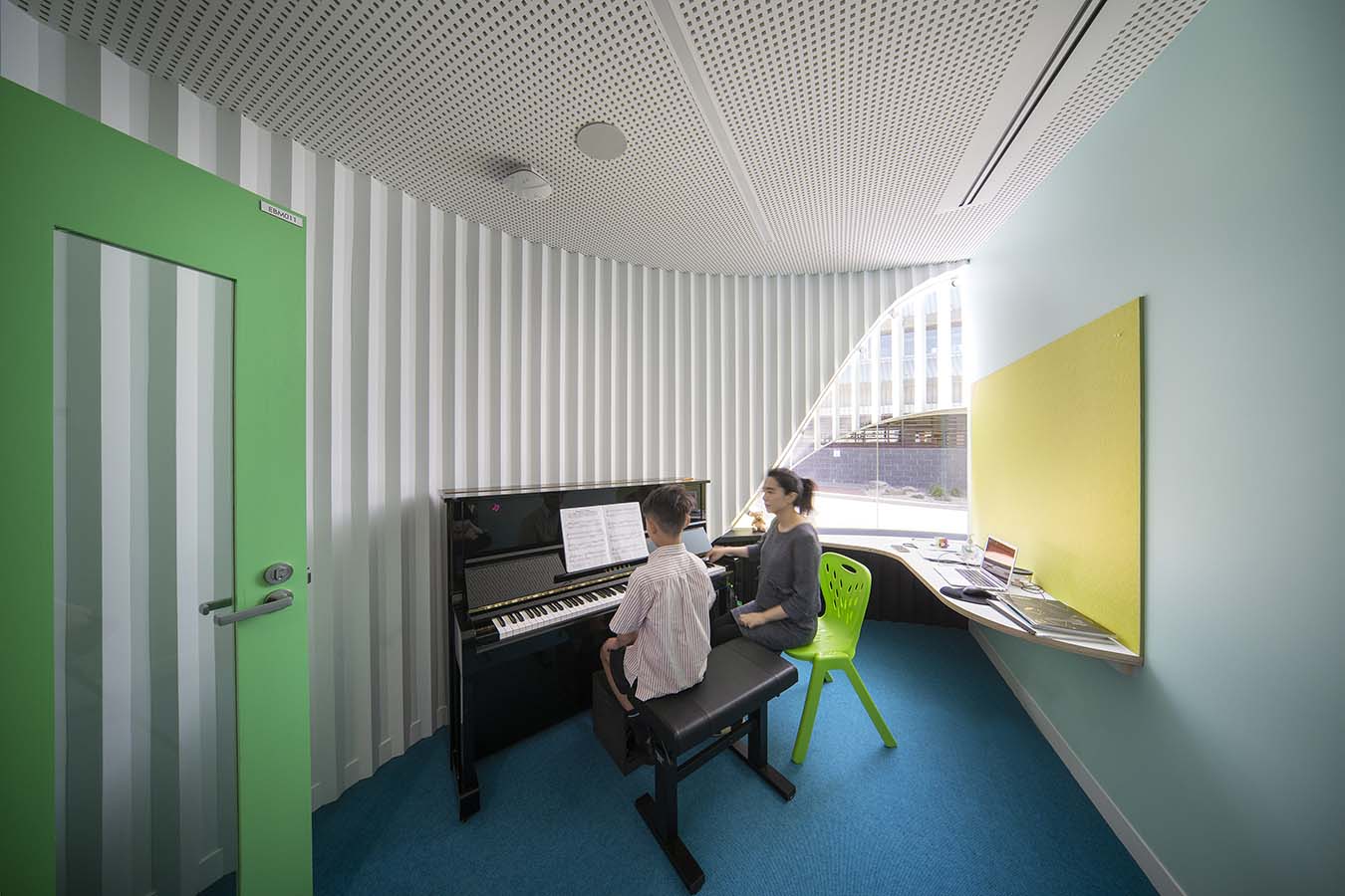 A student playing piano, accompanied by a teacher, in one of the PEGS Music Centre tuition rooms. Photo by John Gollings