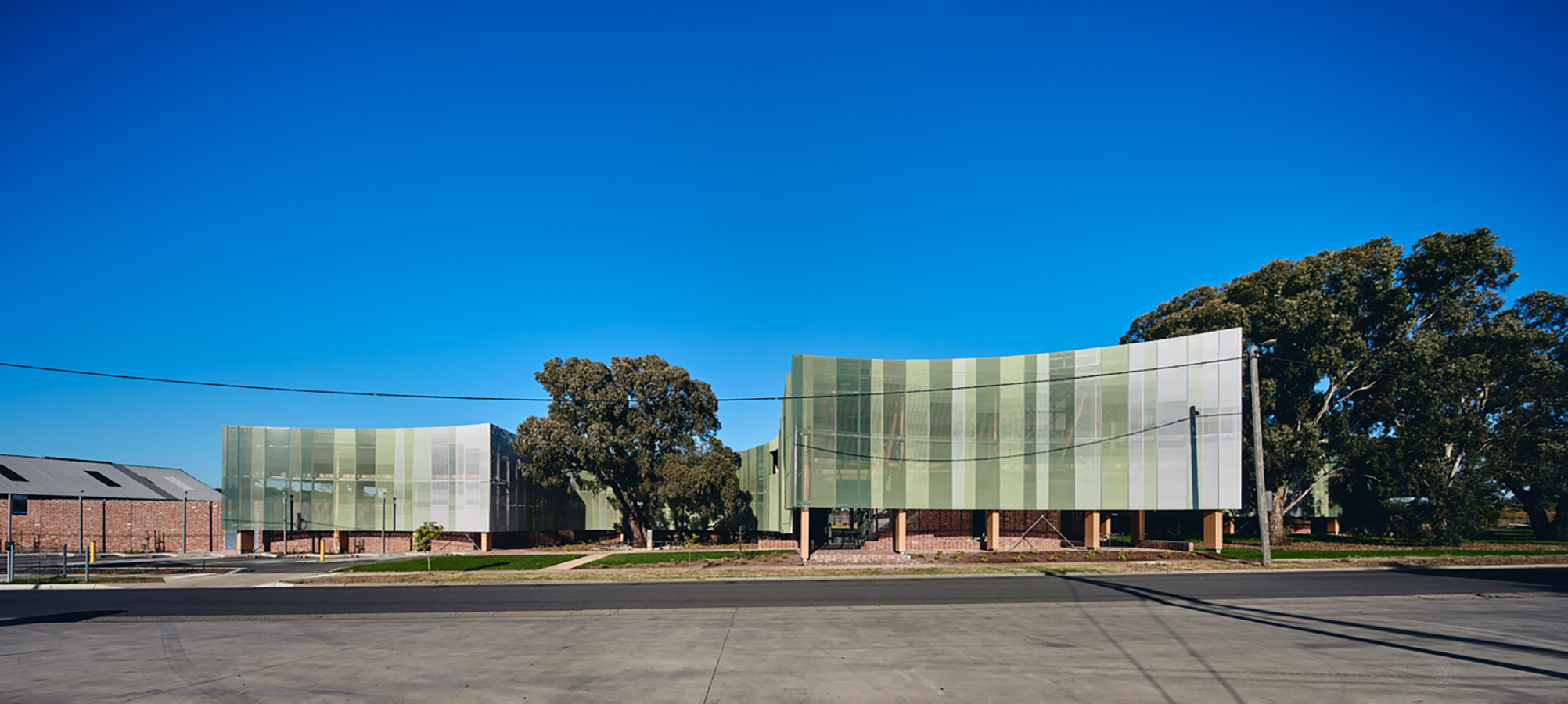 Northern Memorial Park Depot - a graduated green street facade curves behind existing tree canopies.