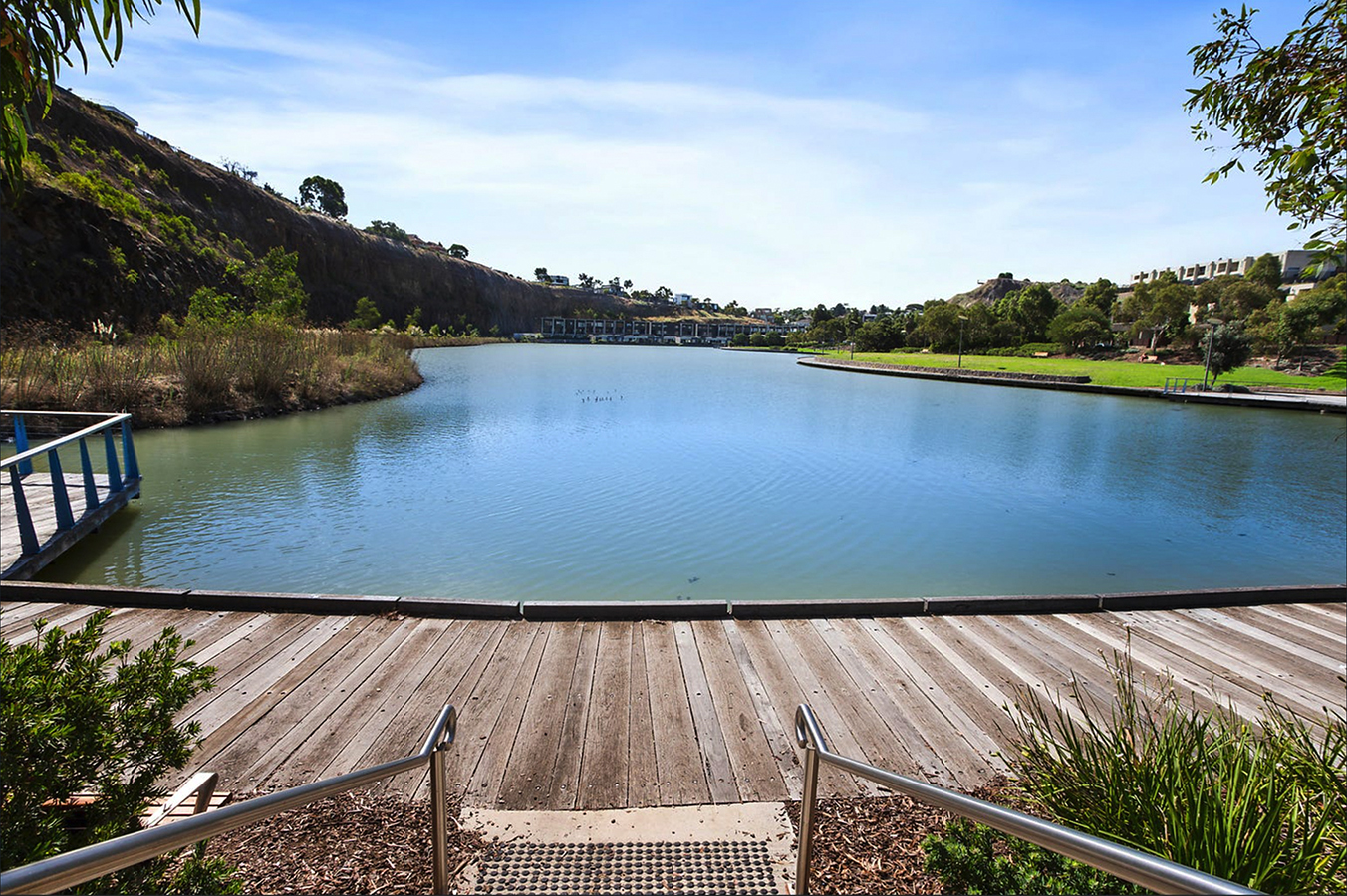 Niddrie Lake with timber boardwalk, cliff face on one side and terrace housing on the right