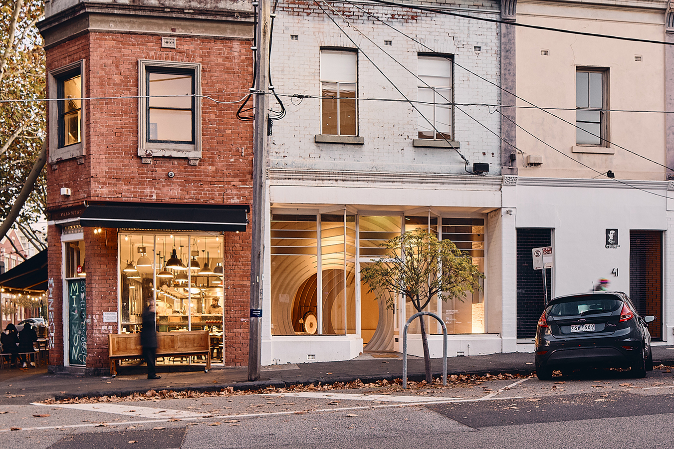 Street view of a building with a café on the left and the curved interior visible through windows.
