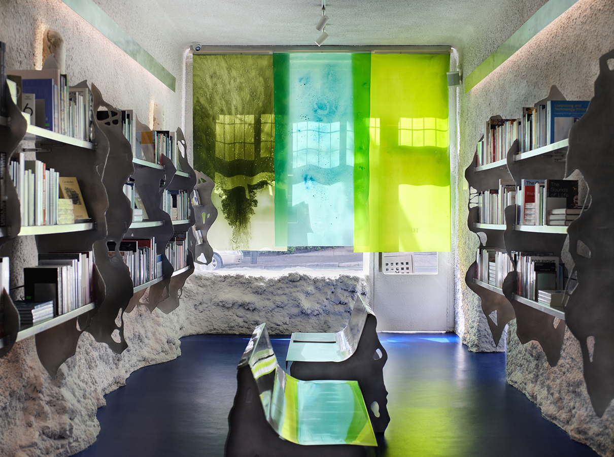 Contemporary bookshop interior with blue floor, algae-based bioplastic panel blinds (expanded), and aluminium furnishings.