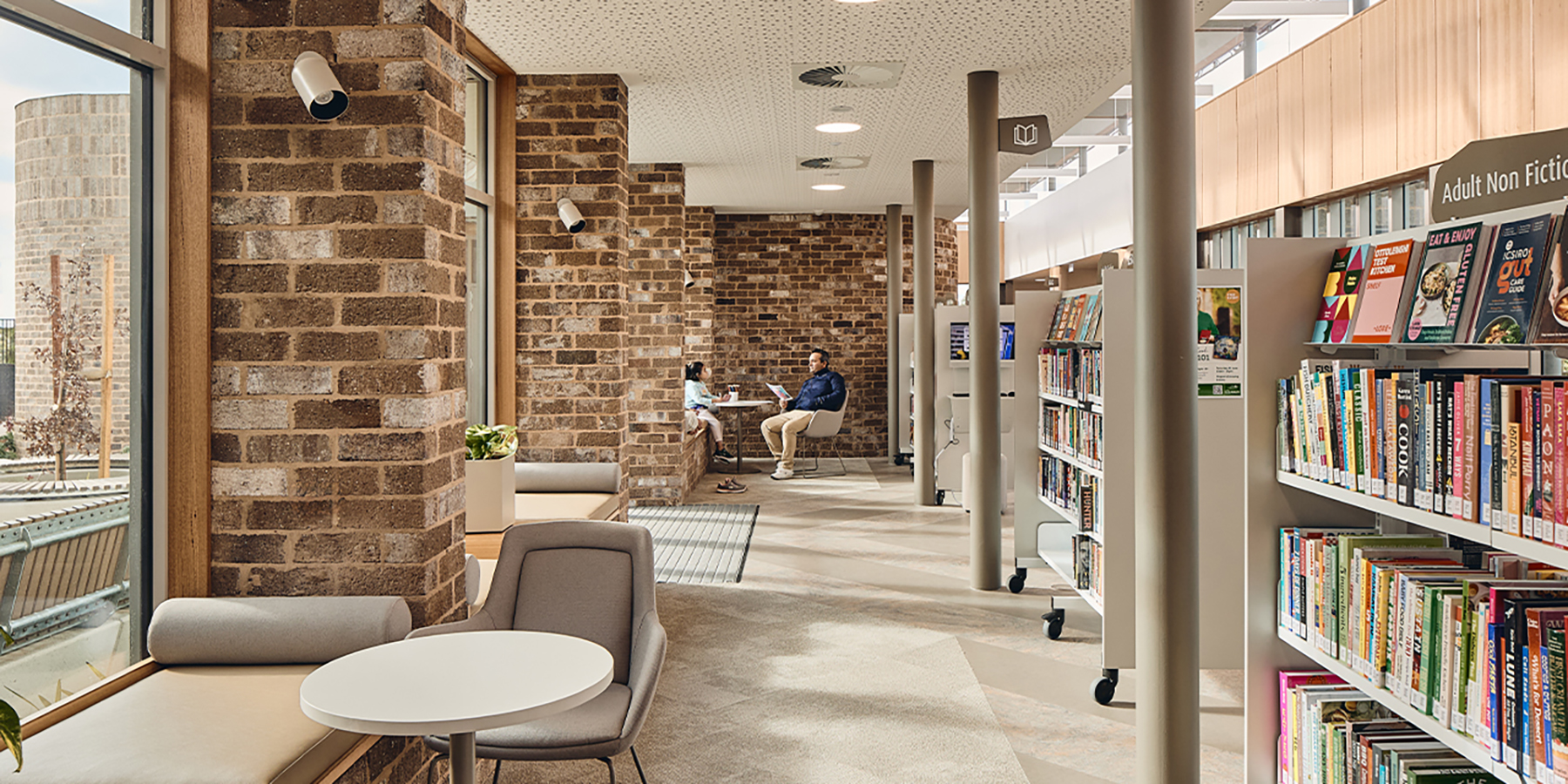 Father and daughter sitting along the reading booths to the left with shelving displayed to the right.