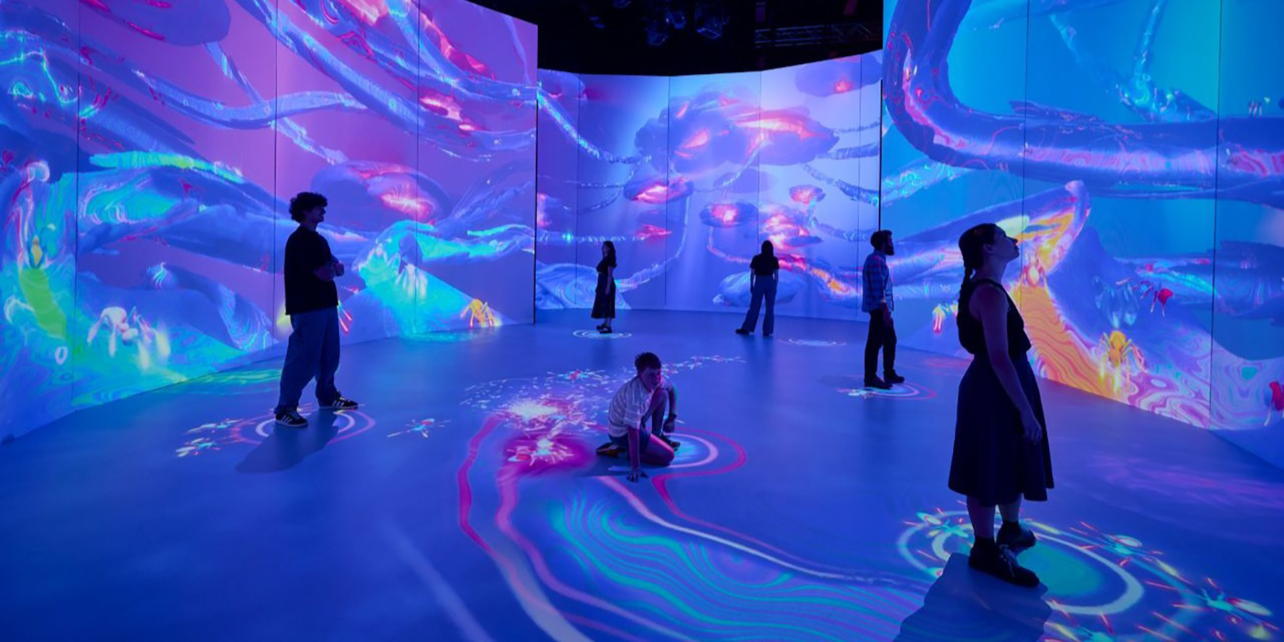 A group of exhibition visitors activating live responsive projections, representing ant pheromones