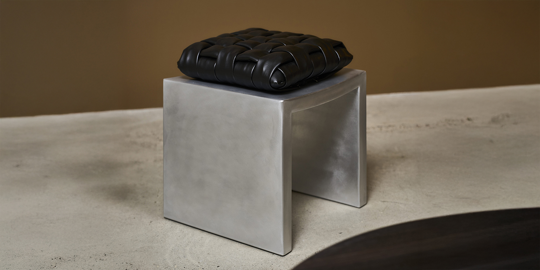 Vault Stool by Locki Humphrey; a simple waxed aluminium seat with an intricate woven upholstery leather cushion on top.