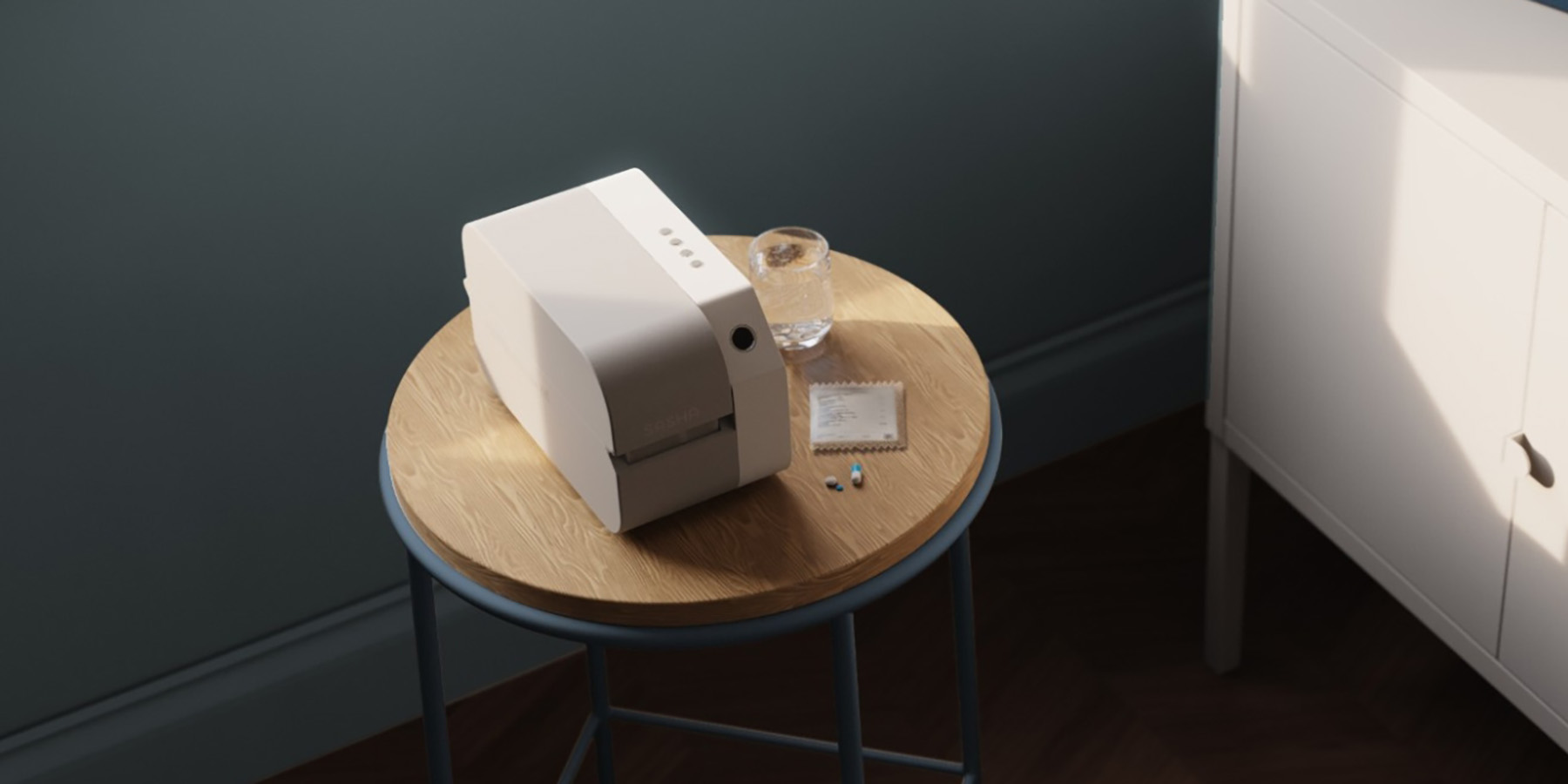 Small medication management device sitting on a side table next to a medication sachet, pills, and a glass of water.