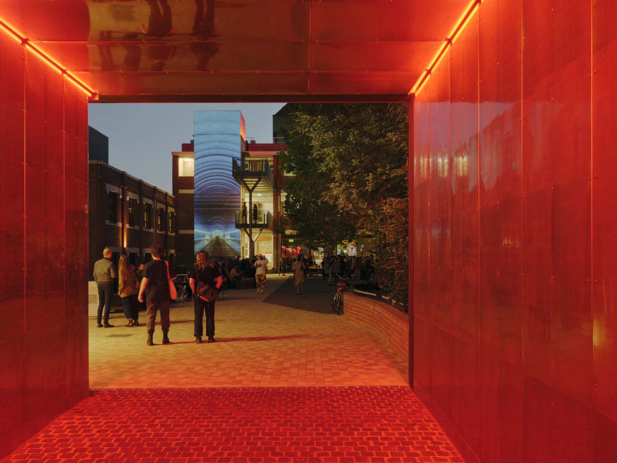 Courtyard event space and Perry St building lift shaft illuminated with projection at dusk. Photo by Tom Ross