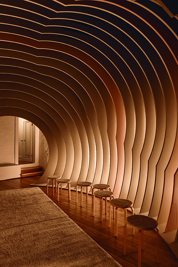 Side view of curved room with stools and warm lighting.