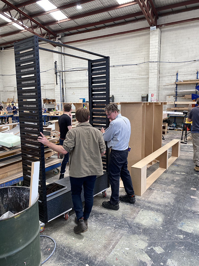 Two men holding up the blade frames in their warehouse, testing the off-the-shelf cable tray frame
