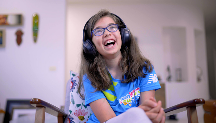 A smiling young person with headphones on