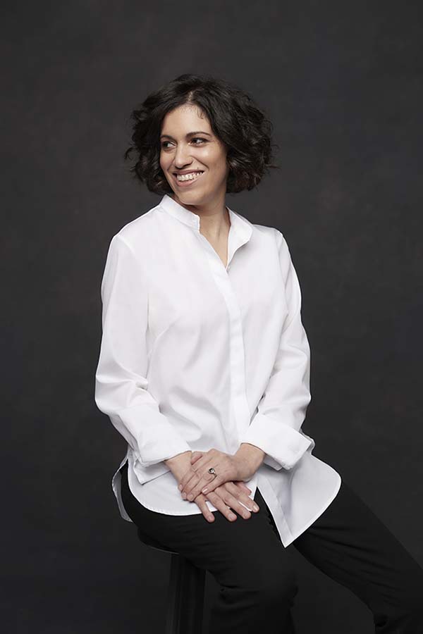 Image of smiling brunette woman in white shirt on black background.