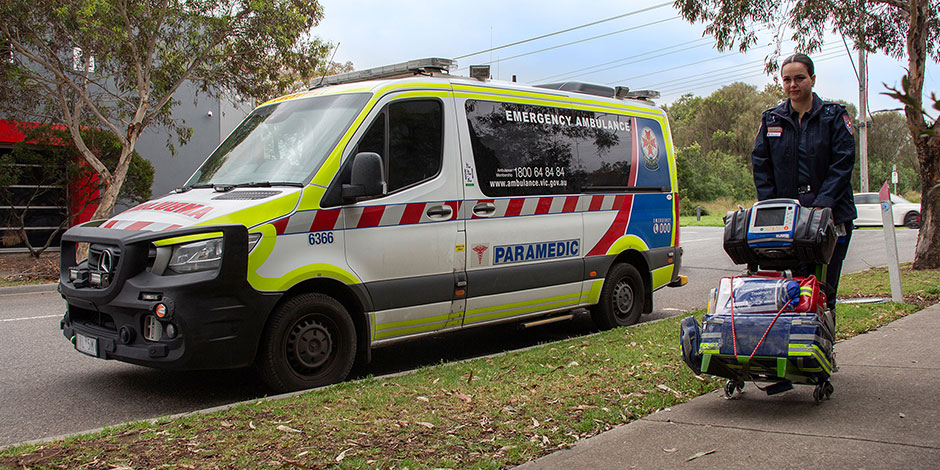 Paramedic pushing the Paramedic Equipment Trolley by the ambulance.