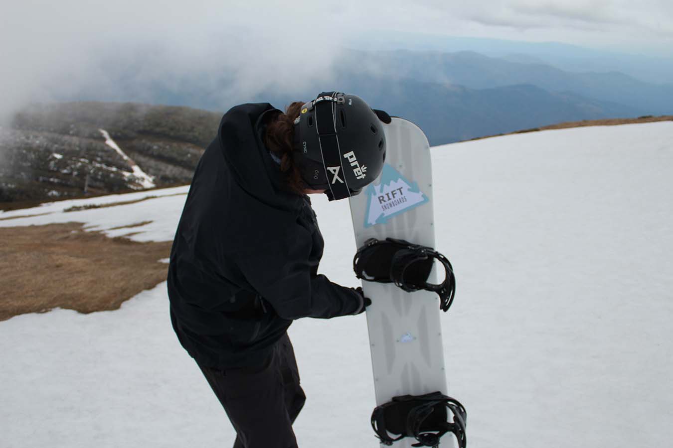 User inspecting snowboard before testing.