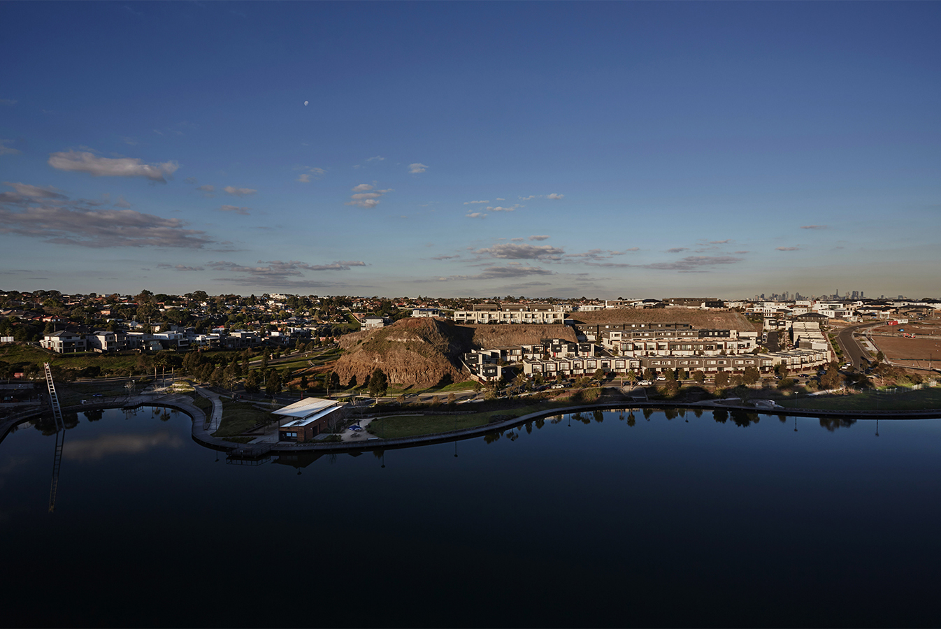 View from the quarry cliff to the lake and several rows of terrace houses, with Melbourne's skyline in the distance.