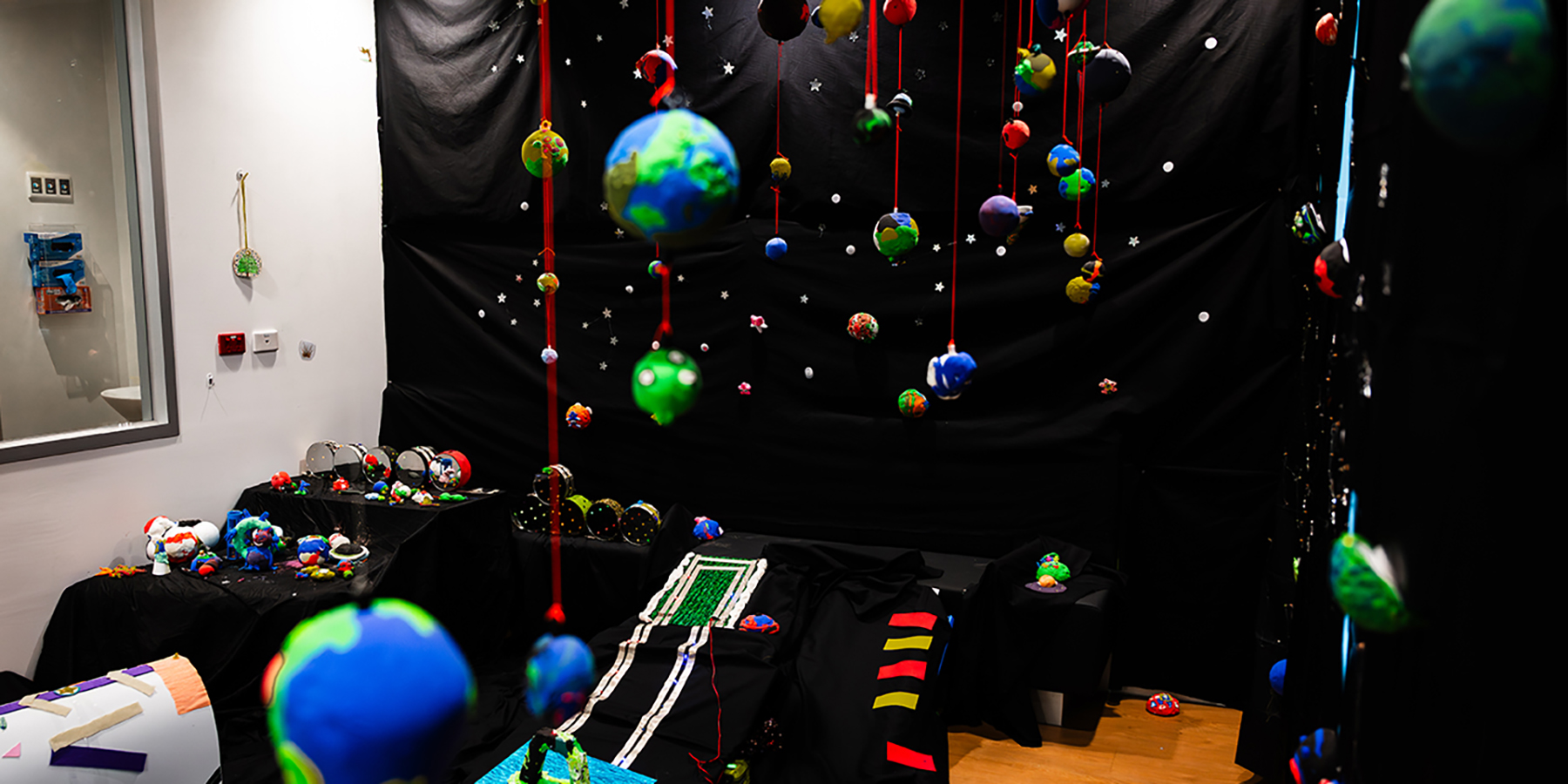 Dozens of colourful planets hang above a galaxy-themed playroom filled with creative installations.