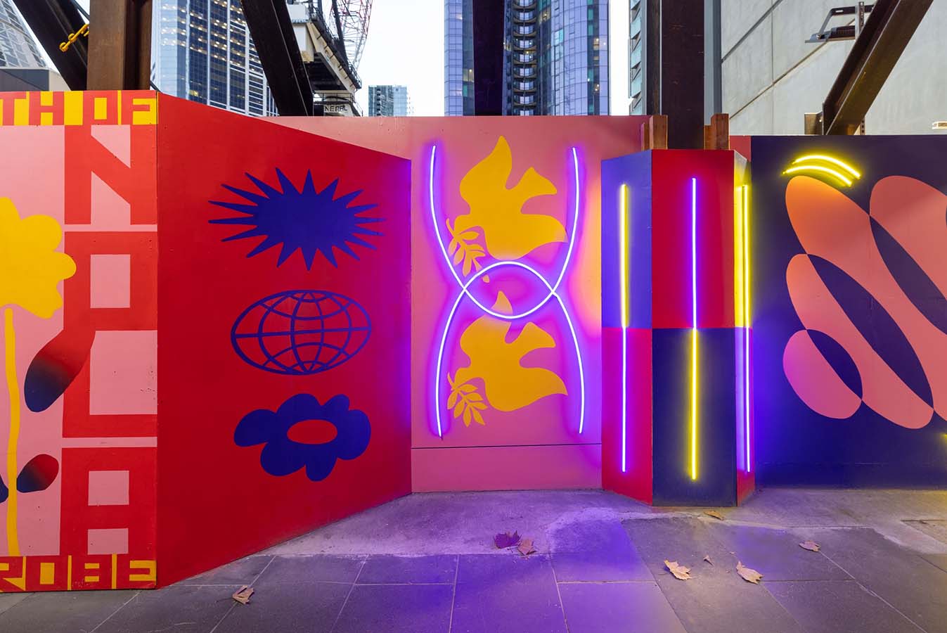 A colourful painted construction hoarding with neon lights