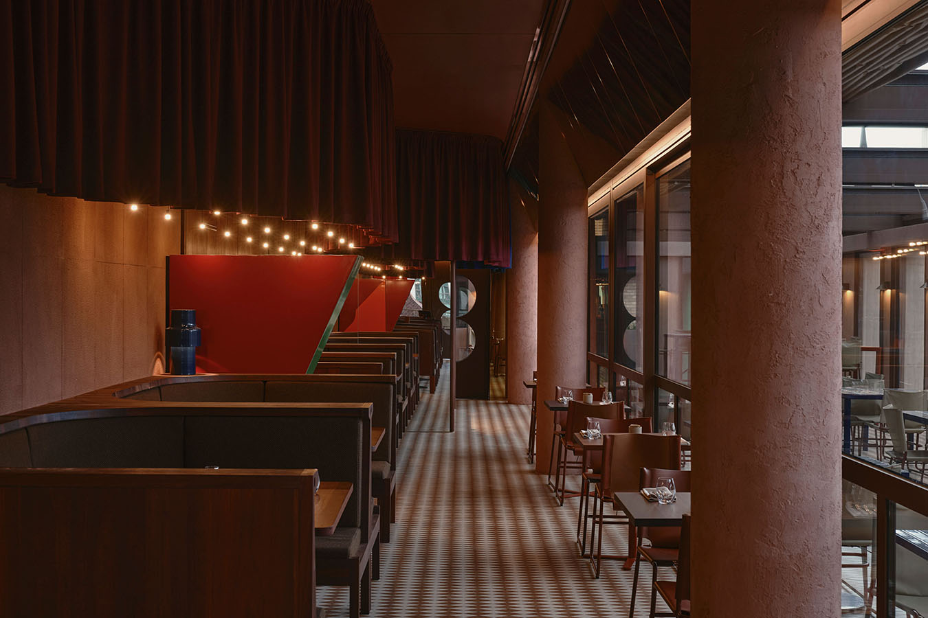 A dining space, with booths to the left, and chairs and tables to the right of a central walkway.