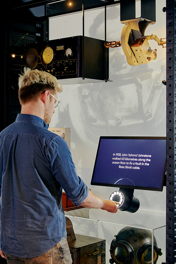 A visitor using the rotary dial interface and reading the storytelling on a LCD screen