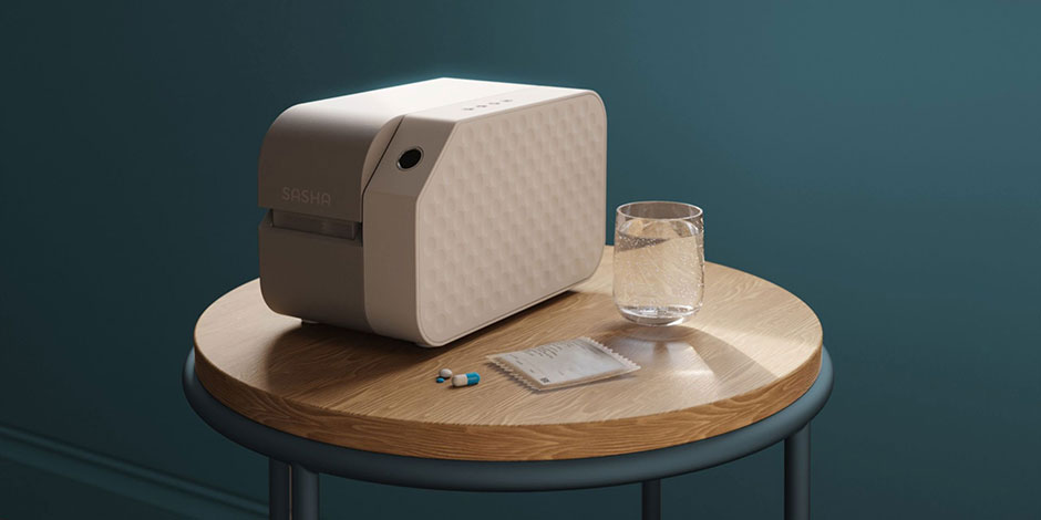 Small medication management device sitting on a side table next to a medication sachet, pills, and a glass of water.