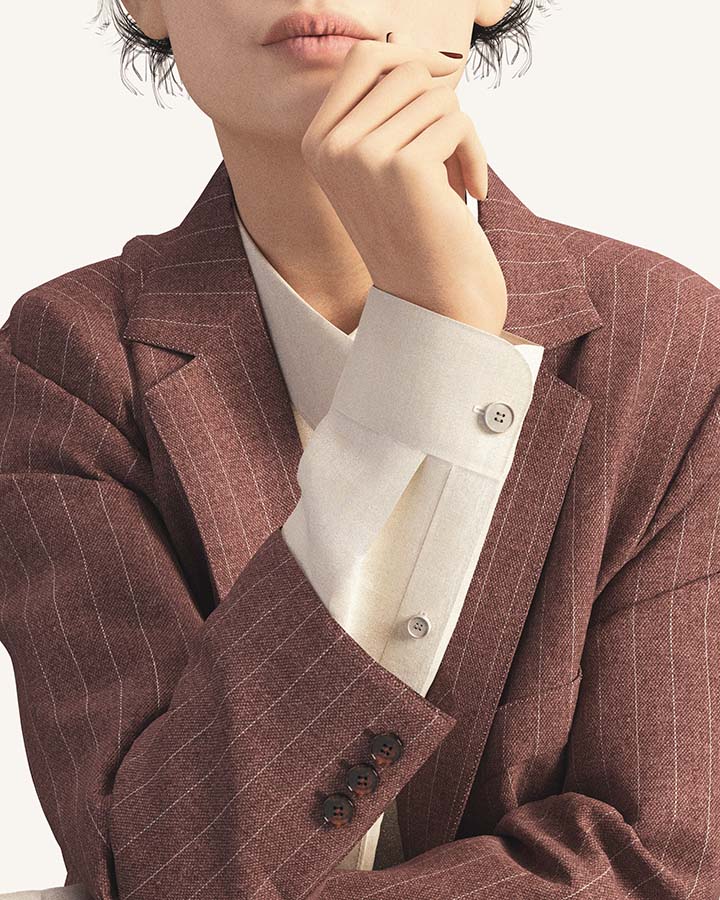 Female avatar close up from lips to elbow, wearing dusty pink pinstripe suit jacket, right hand up by chin, left on elbow.