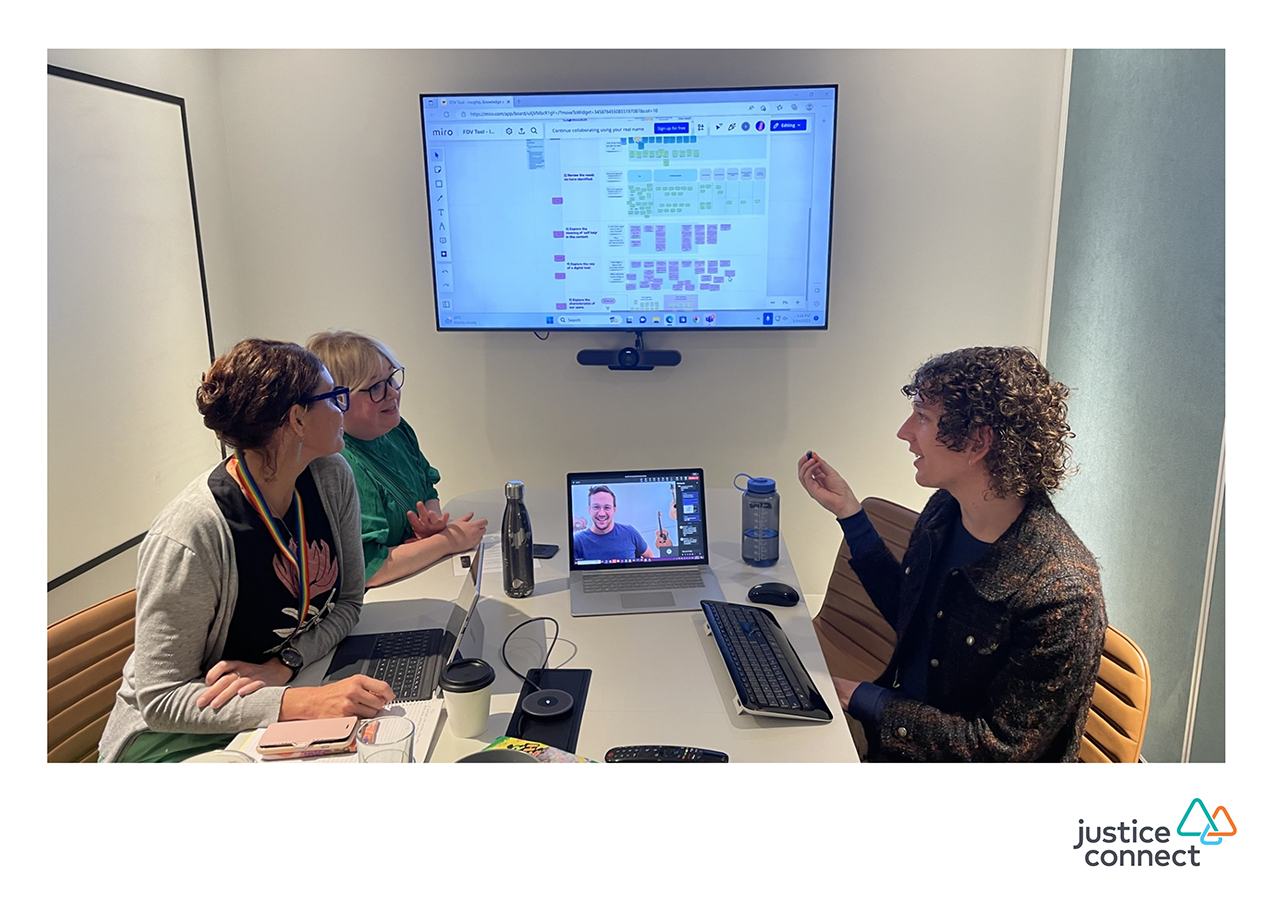 Three people in a meeting looking at a television screen