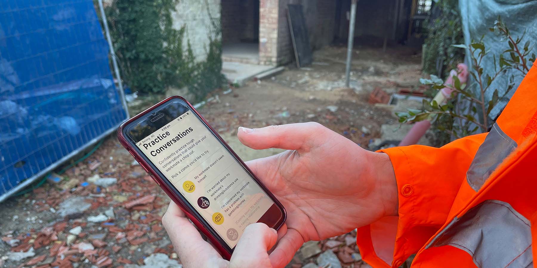 An image of a construction worker using Chop Out Convos on an iPhone SE 2020. He is on a construction site and wearing hi vis